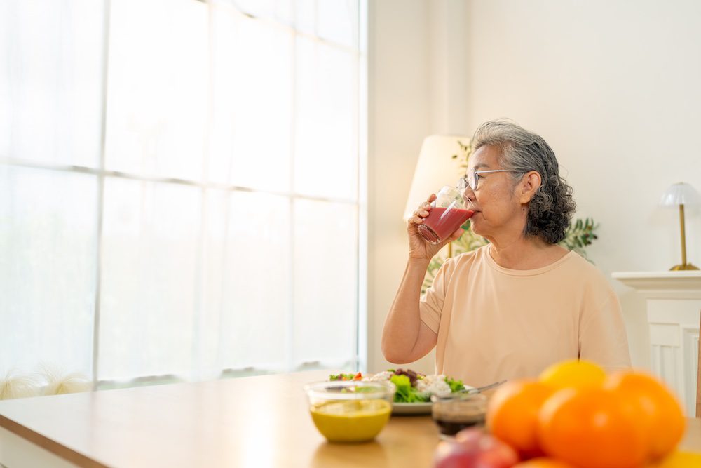 Asian woman drinking orange juice representing The Best Fruits and Vegetables for Seniors
